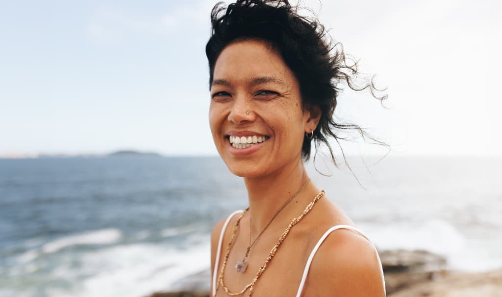 A woman laughing beside the sea
